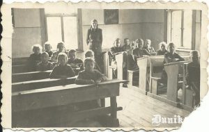  • Dunikas-Sudargu I pakāpes pamatskolas klasē 1954. gada 15. maijā (vairākas klases kopā mācās vienā telpā). Labajā pusē 1. solā .........., 2. solā Sproģe Aira, nav redzama Veisbuka Emīlija, 3. solā Sleže Natālija un Bruže Velta, 4. solā Štībelis Vilnis, .........., Aigars Alberts, 5. solā Drēže ..... (?). Kreisajā pusē 1. solā Reijere Aina, 2. solā .......... un .........., 3. solā .......... un .........., 4. solā Bruže Zenta (?) un Kūpele Inta (ar bizēm), 5. solā .......... . Stāv audzinātāja A. Haritonova (Kukuka).