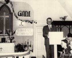 KĀRLIS JANEKS. svētku rīkotājs, vada apsveikumu daļu, vispirms pieminot Brāļu Draudzes vadītājus, darbiniekus un draudzes locekļus, kas jau Mūžībā – dziedot “Kādā nu mierā”.